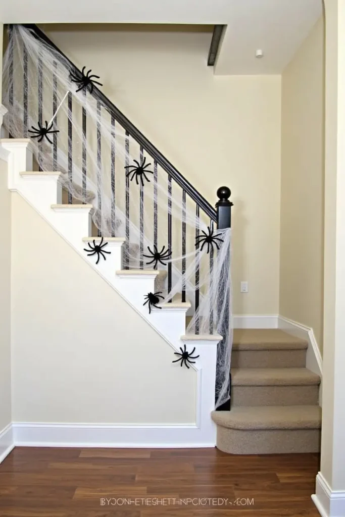 “Halloween staircase wrapped in cotton webs with giant spiders, creating spooky vertical party decor.”